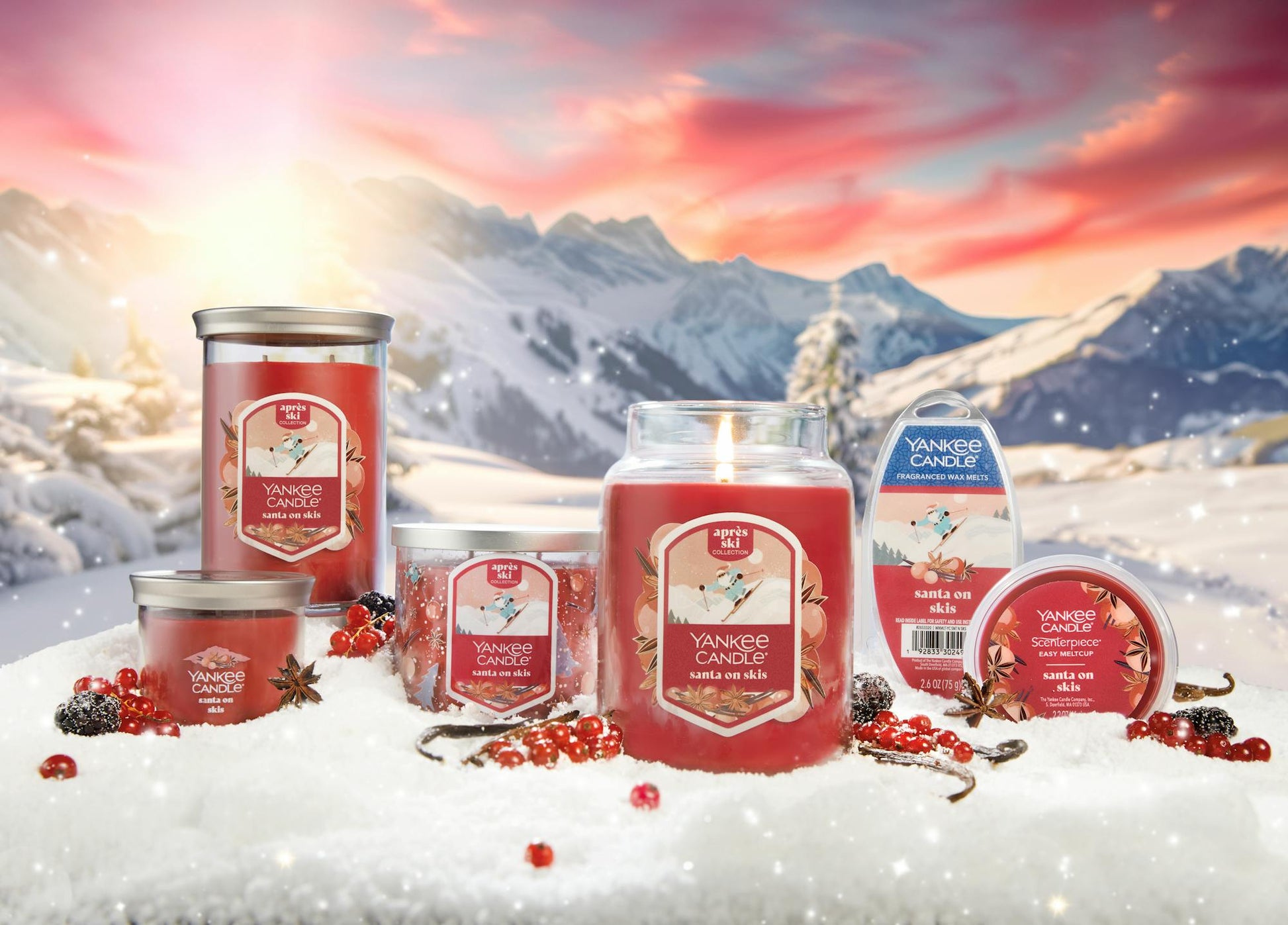 an array of santa on skis products on a snowy surface with vanilla beans and cardamom and red berries with mountains in distance