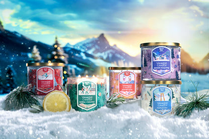 Apres Ski Collection Santa on Skis 3-Wick Candle, Holiday Winterfest 3-Wick Candle, Slopeside Spritz 3-Wick Candle, Summit Stargazing 3-Wick Candle, and Fresh Powder 3-Wick Candle in snow surrounded by mountains, slices of lemon, and branches